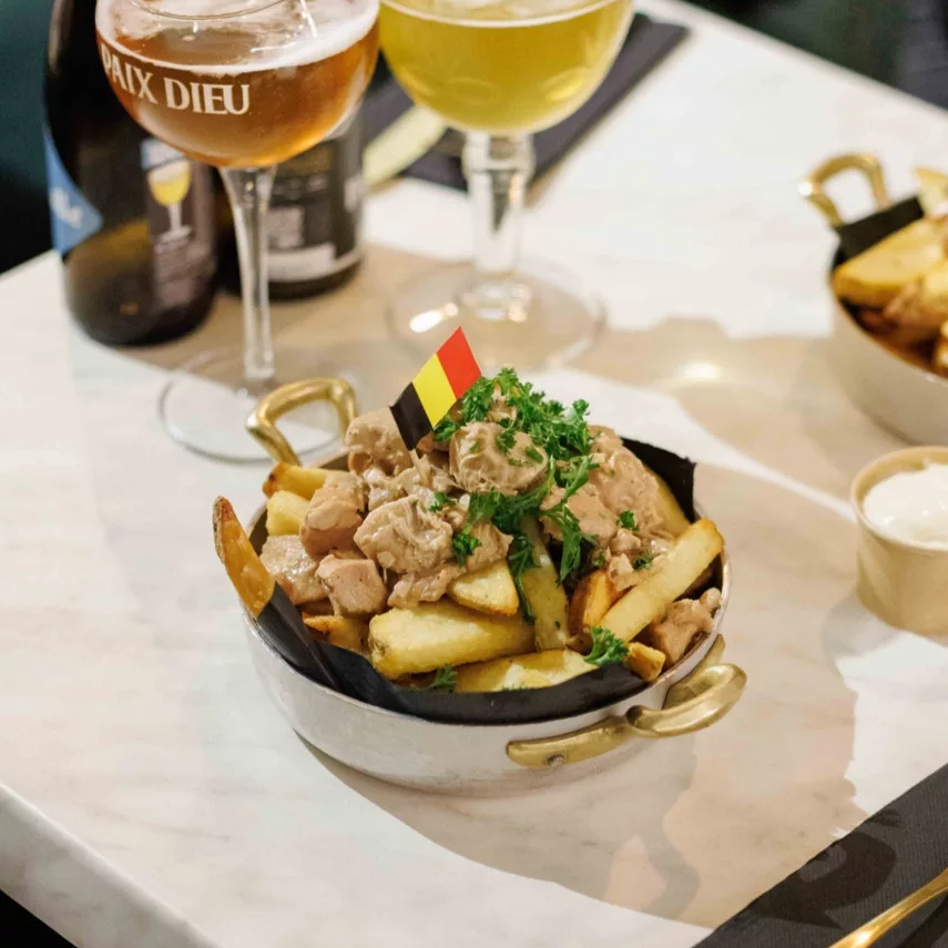 A box of fries with a glass of wine on a table.