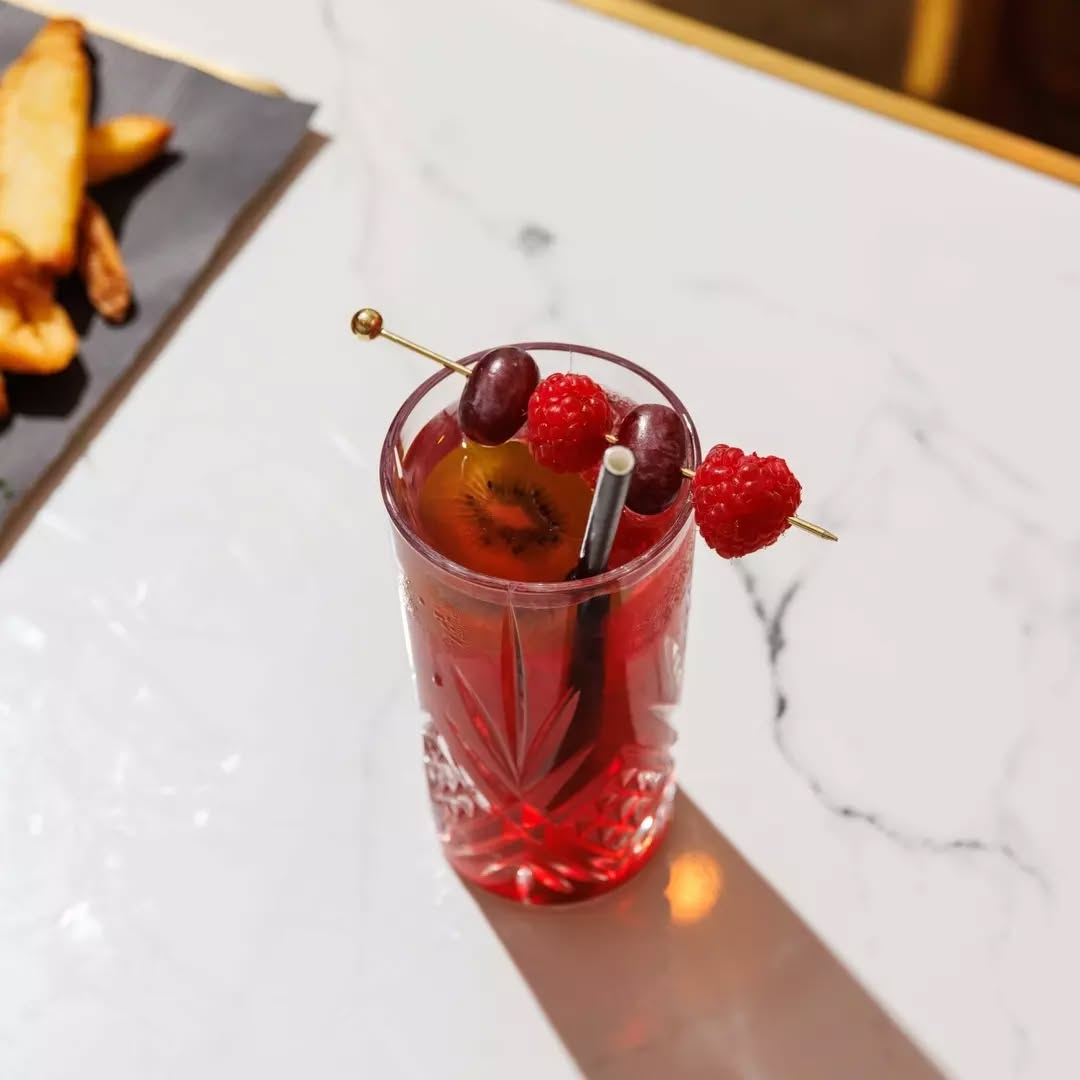 A hand holding a small piece of food with a green leaf on top.